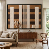 Elegant Forgotten Gateway textile art hanging above a plush sofa and wooden sideboard, showcasing the contrast of cream and brown wool textures.