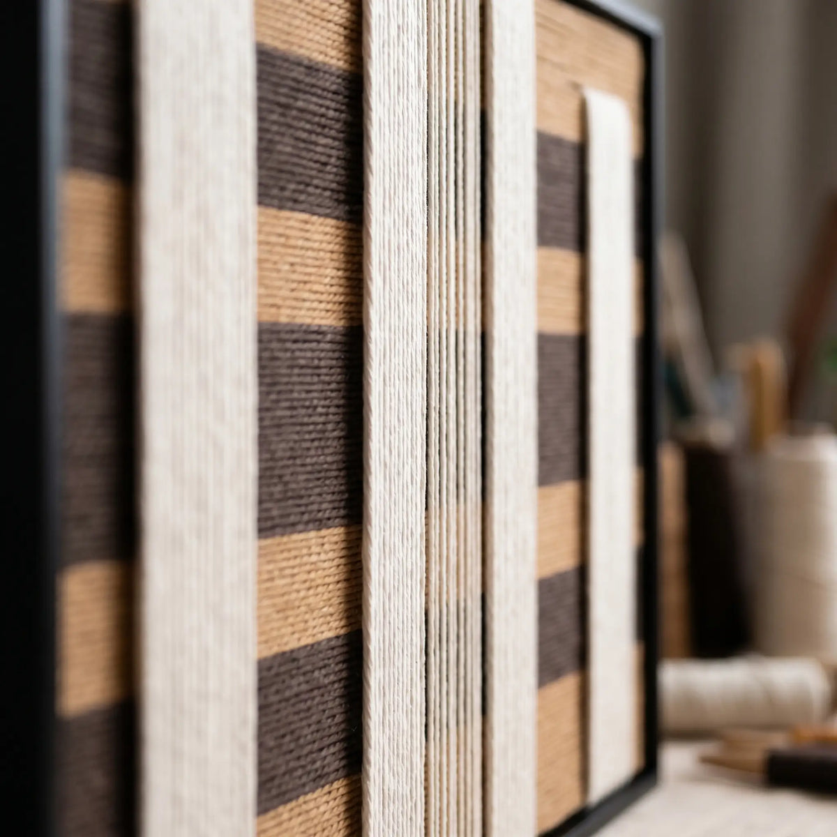 Macro shot of the Forgotten Gateway hand-woven wool tapestry displaying intricate cream and dark brown geometric texture in a black frame.