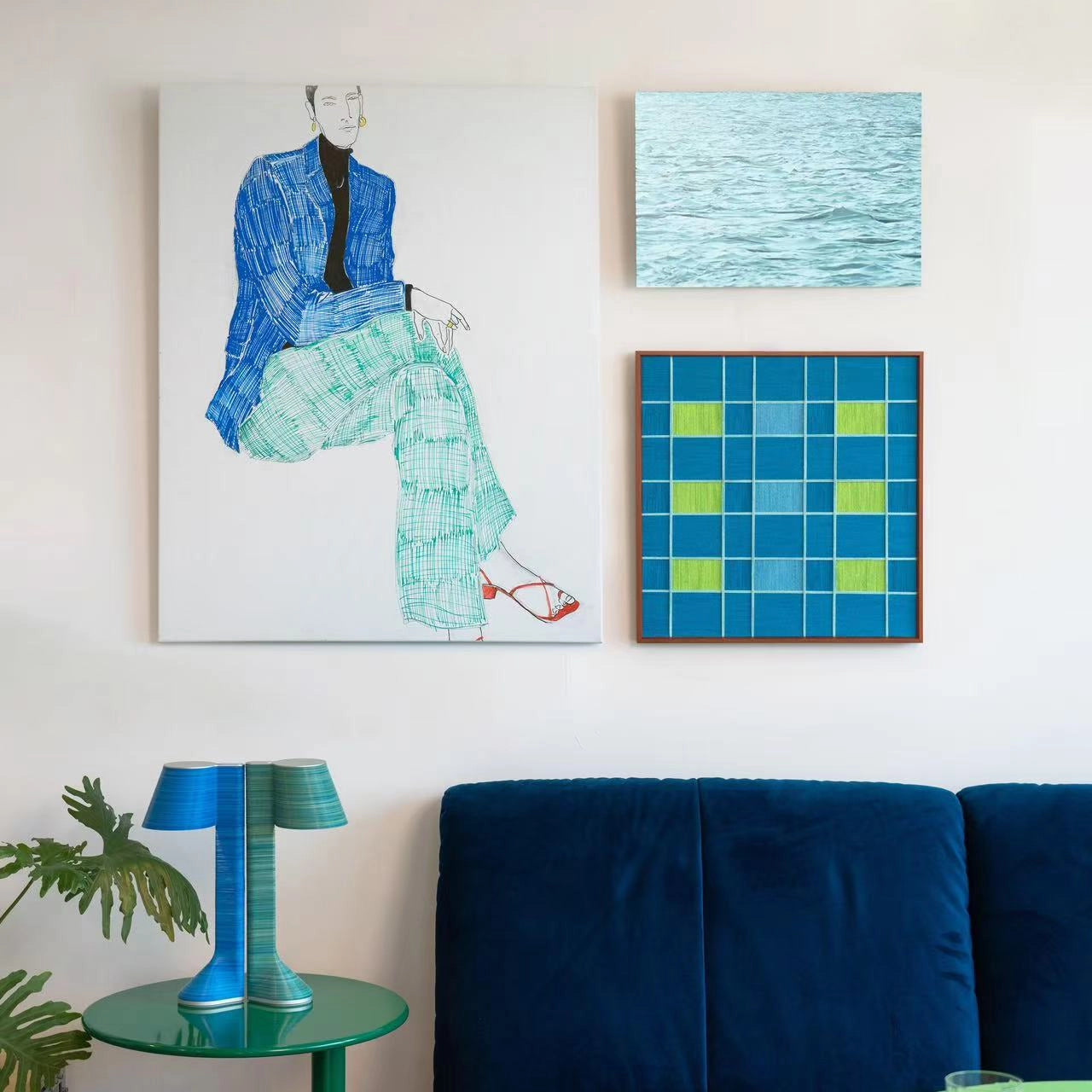 A stylish gallery wall featuring the woven checkerboard art piece alongside a large figure painting, styled above a blue sofa in a modern living room.