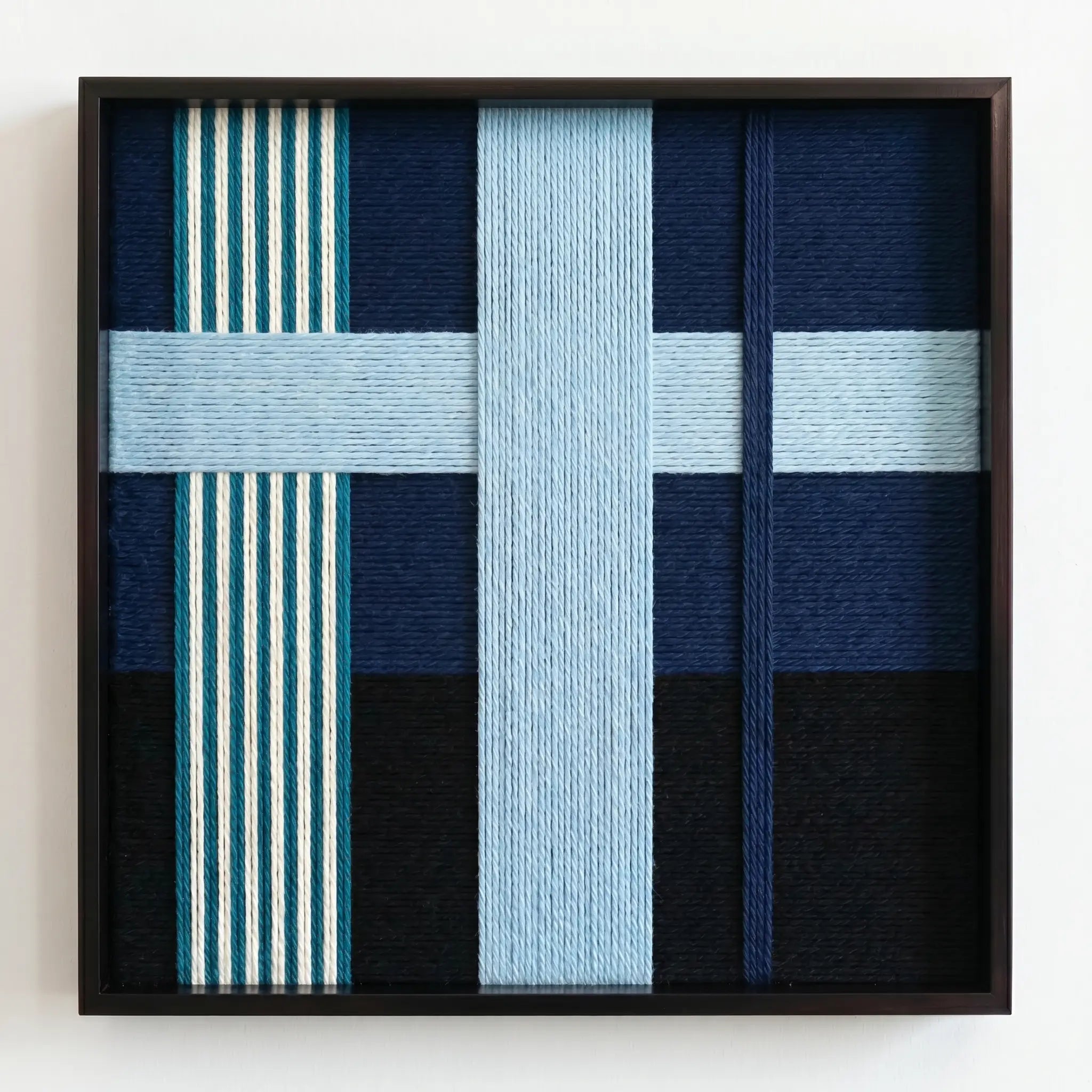 Frontal studio shot of the Glacial Stationeries wool wall art featuring a light blue cross pattern and striped accents in a black frame.