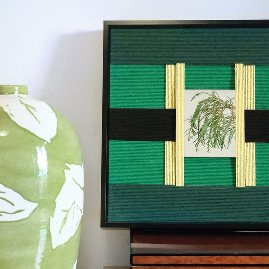 Close-up of Green Glow hand-woven yarn art with a hand touching the surface, emphasizing the looped wool texture and crisp stripe edges
