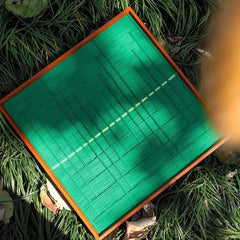 Angled close-up of Green Shadow Weave wall art highlighting the tactile looped wool texture and crisp transitions between green panels and the yellow stripe
