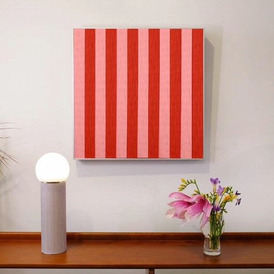 Hana & Alice hand-woven yarn wall art with bold red and light red vertical stripes, hung above a console table with lamp and fresh flowers to add a vibrant focal point
