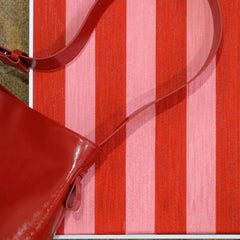 Close-up of Hana & Alice wall art with a red ribbon accent, revealing detailed yarn fibers and subtle shade variations in the stripe pattern
