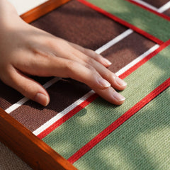 Close-up of a hand touching the soft wool surface, emphasizing the high-quality handcrafted texture and material of the Gift Ribbon art piece.