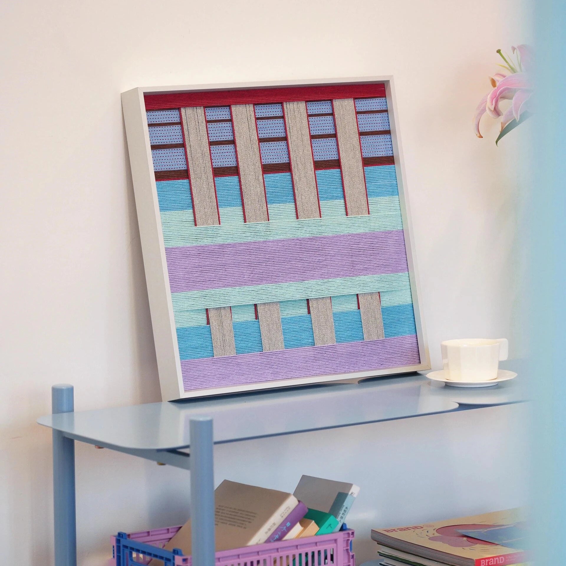 Hanosen Anji yarn wall art displayed beside a laptop and notebook, emphasizing its modern color palette and precise weave
