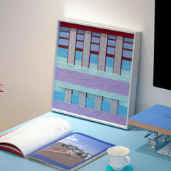 Close-up of Hanosen Anji yarn wall art revealing tight stitch detail and the interplay of pastel and red grid fibers
