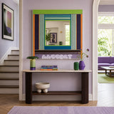 Hidden Forest green, purple, blue, and orange yarn-framed mirror displayed above a console table in a bright entryway.