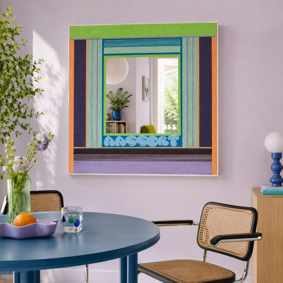 Hidden Forest green, purple, blue, and orange yarn-framed mirror displayed above a round blue table in a modern dining room.