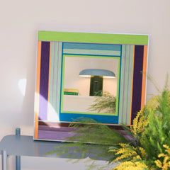 Hidden Forest yarn mirror art displayed on a shelf beside books and foliage, highlighting its compact square form and tranquil color palette.
