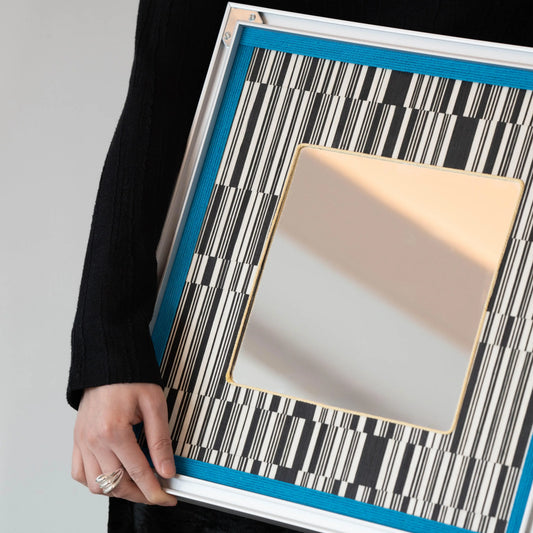 Close-up of Inception SQ016 showing black-and-white yarnwork, blue border and silver metal frame.