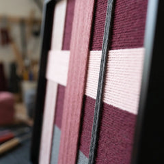 An angled close-up view of the framed fiber wall art showcasing the structural multi-directional layering and dimensional depth of the wool yarn.