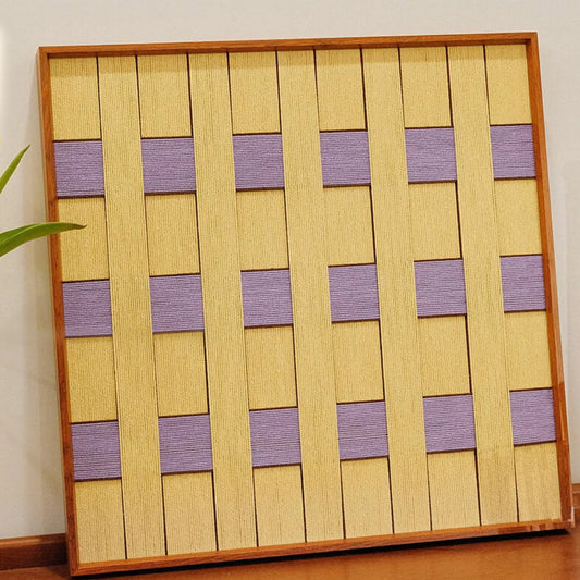 Angled close-up of Lover’s Moonlight Violet yarn wall art highlighting the tight weave at the intersection of lavender and yellow stripe panels
