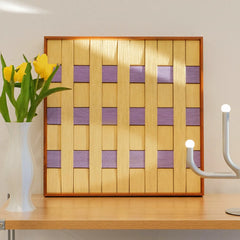 Lover’s Moonlight Violet hand-woven wool yarn wall art with alternating lavender and buttery yellow stripes in a natural wood frame, displayed on a console table with vase and lamp
