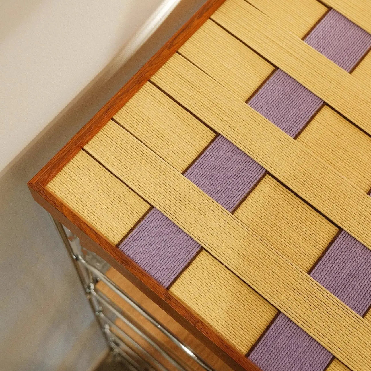 Flat lay of Lover’s Moonlight Violet yarn wall art on wooden surface, emphasizing its precise square format and harmonious stripe design
