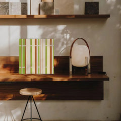 March Tree yarn wall art styled on a desktop shelf alongside books and a vase, showcasing its crisp stripe pattern and compact square format.

