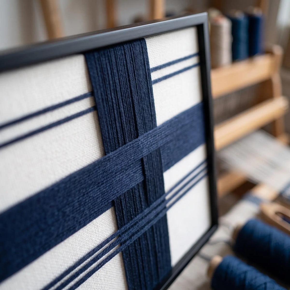 Detailed macro close-up of the Midnight Axis hand-woven wool tapestry featuring navy blue geometric lines against a neutral canvas.