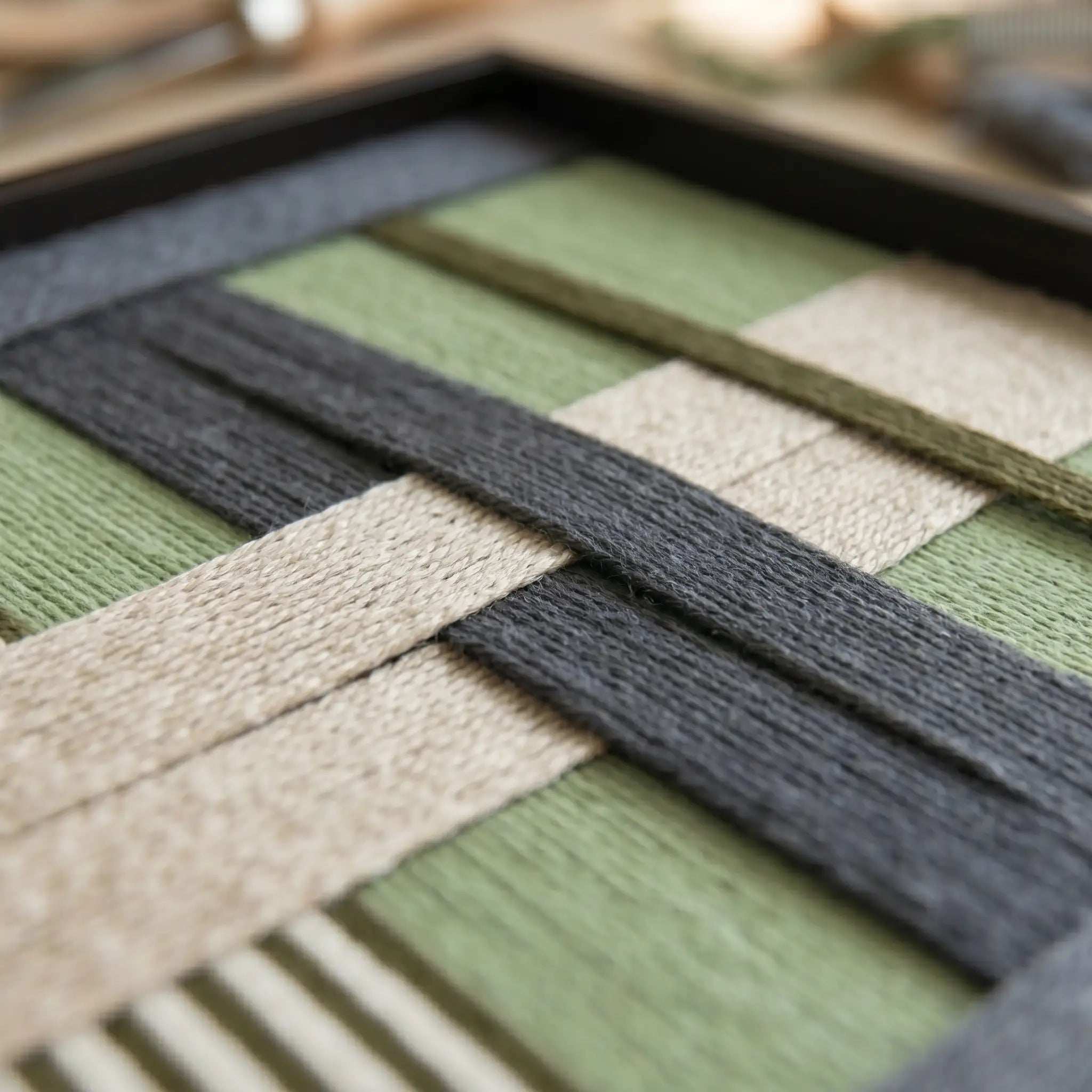 Macro shot of the Misty Forest hand-woven wool art highlighting the interlocking sage green, charcoal grey, and beige hand-wrapped yarn patterns.