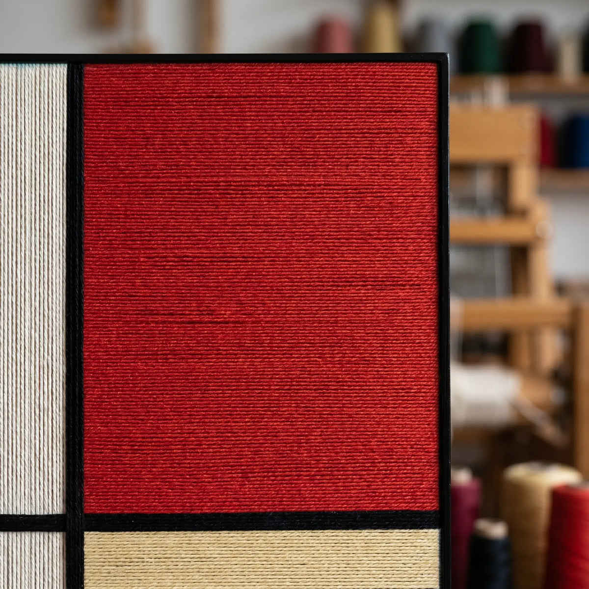 Macro close-up of the vibrant red soft cotton cord fibers and thick black lines of the textured geometric wall art tapestry.