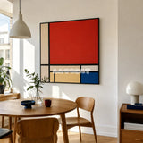 Mondrian red blue yellow and black textile wall art styled above a round wood table in a sunlit modern dining room.