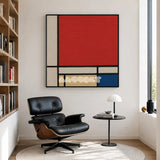 Mondrian red blue yellow and black textile wall art displayed above a leather lounge chair in a bright modern reading corner.