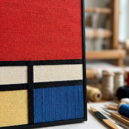 Close-up of the blue and yellow hand-woven sections showing the high-quality craftsmanship and dense textile texture of the framed art.