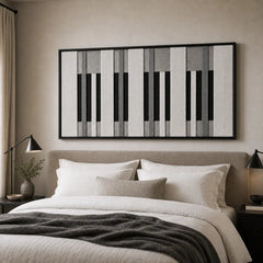 A beautiful framed piano-key inspired hand-woven wool tapestry displayed gracefully above a styled bed in a cozy, neutral bedroom.