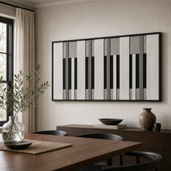 The striking black and white hand-woven wool tapestry provides a dramatic focal point over a dark wooden dining table in a bright dining room.