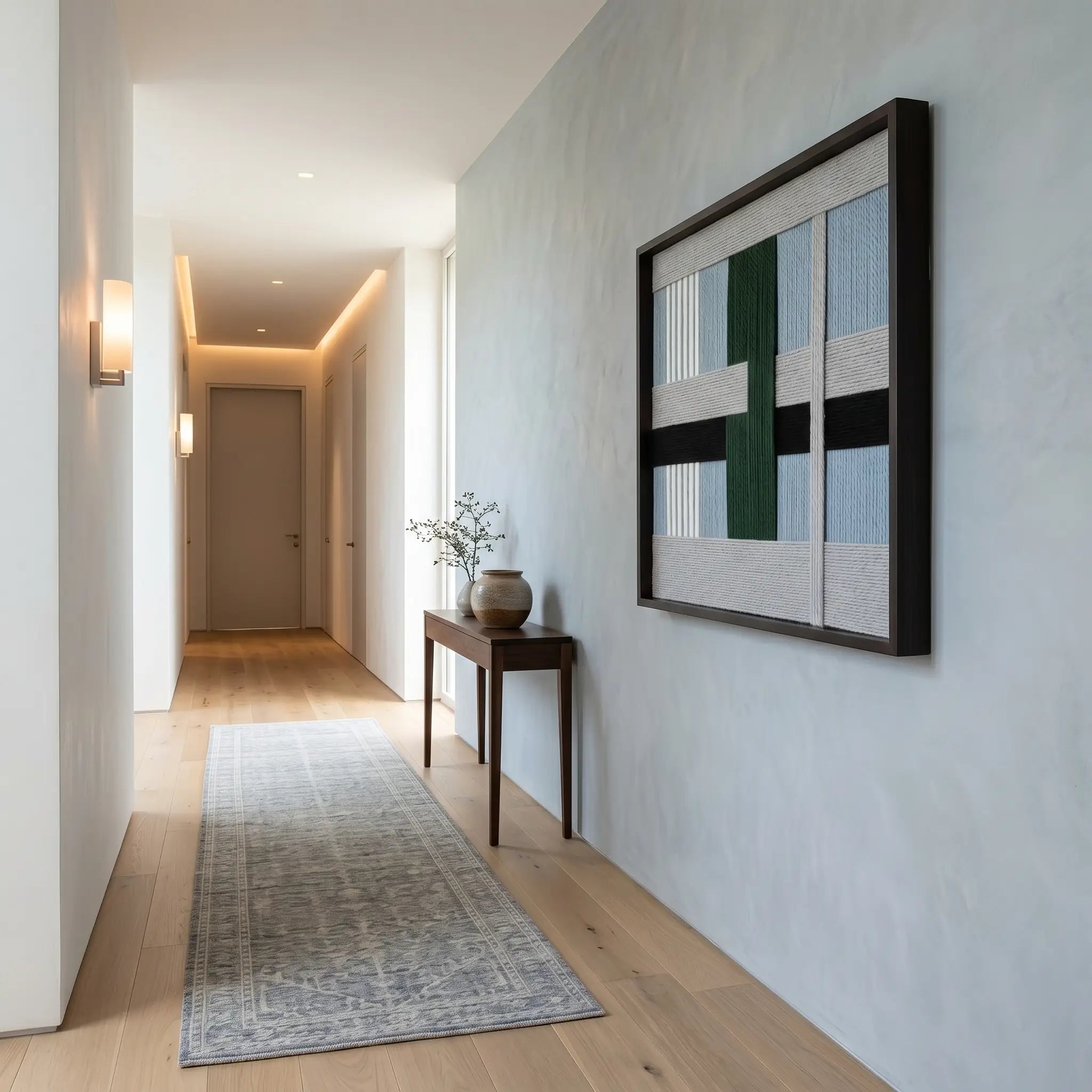 Square framed wool wall art hanging as a sophisticated focal point in a minimalist hallway with a long grey runner rug.
