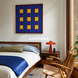 Moonlit Windows blue, yellow, and red geometric yarn wall art displayed above a wooden bed in a sunlit modern bedroom.