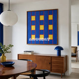 Moonlit Windows blue, yellow, and red geometric yarn wall art displayed above a wooden sideboard in a modern dining room.