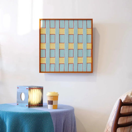 Push Open the Afternoon Window wall art with alternating pastel blue and buttery yellow yarn stripes in a square grid pattern and natural wood frame
