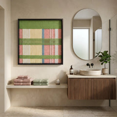 Large square Pastoral Lullaby fiber wall art with pastel green, pink, and yellow woven patterns hanging in a modern bathroom next to an arched mirror.