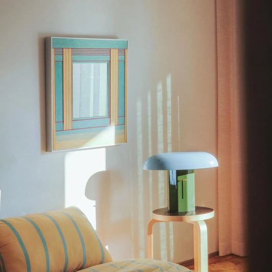 Pear Blossom Tree mirror art styled on a tidy desk beside a notebook and cup, showcasing its compact square form and fresh green‑wood stripe composition.
