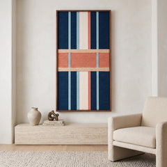 Modern living room interior showcasing a vertical hand-woven wool tapestry featuring dark blue and cream yarns with a salmon band, hanging above a stone console table.