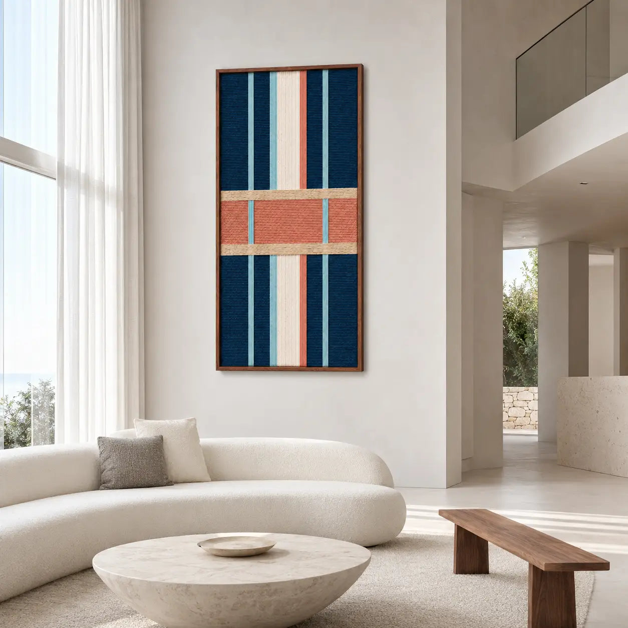 Spacious modern living room decor displaying the geometric hand-woven wool tapestry mounted on a clean white wall near a curved sofa and coffee table.