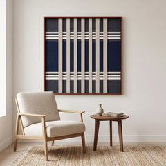 A cozy reading nook featuring the Polar Meridian hand-woven wool tapestry displayed on a white wall above a wooden armchair.