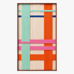 Full product shot of the hand-woven wool wall art in a sleek metal frame, highlighting its geometric pattern of cream, teal, orange, and pink yarn structures.