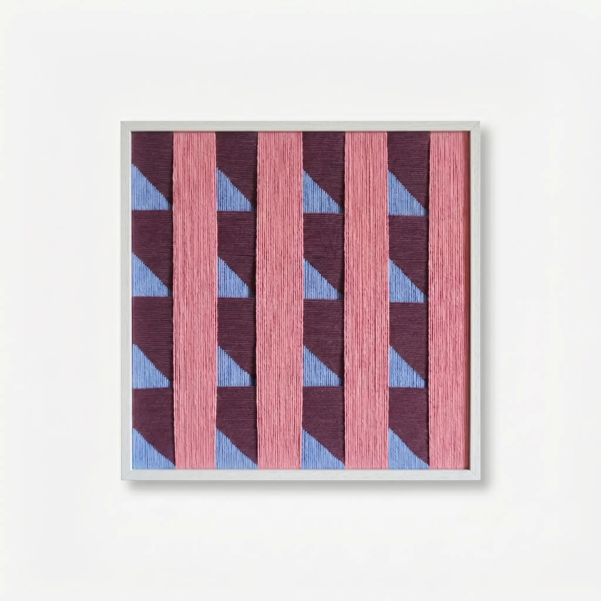 Product view of Whispering Bricks textured fiber wall art made with soft cotton cord with dusty pink vertical bands and purple-blue geometry.