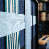 Angled craftsmanship detail of Glacial Stationeries fiber art highlighting its structural multidirectional yarn layering.