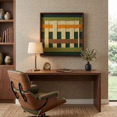 Hand-woven wool wall art with green, mustard, and brown geometric patterns hanging above a dark wood desk with a lounge chair.