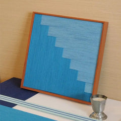 Angled view of Radiant Azure yarn wall art highlighting its precise geometric stitch pattern and warm natural wood frame
