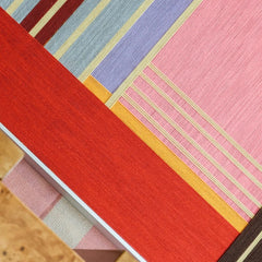 Rainbow Hearts wall art styled with red candles and glassware on a wooden surface, showcasing playful multicolor accents and natural frame contrast
