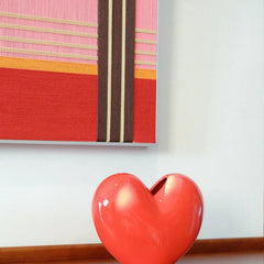 Close-up of Rainbow Hearts yarn wall art showing precise stitch detail and crisp color transitions between the red and pink stripe panels
