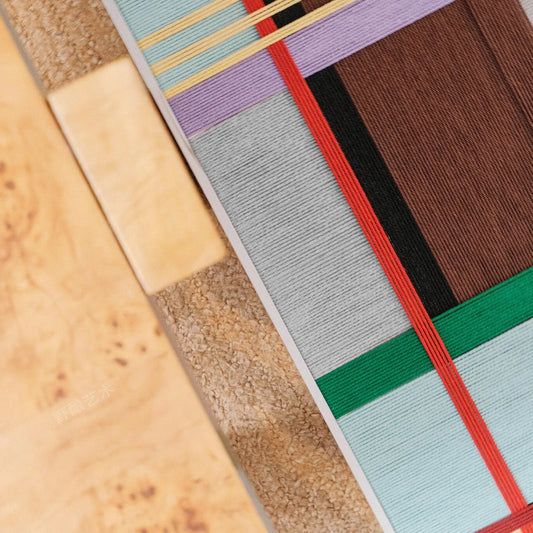 Close-up of City Rhythms RE012 textile art showing intersecting light blue, brown, red, green, and lavender soft cotton cord lines.