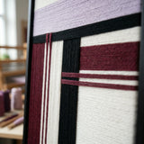 Angled close-up of Midnight Opera RE025 framed textile art showing dimensional lavender and burgundy yarn layering.