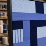 Angled close-up of Nordic Tide RE028 textile art showing its black frame and raised dimensional blue yarn texture.