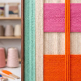 Macro detail of Broadway Blocks textured textile art showing cream vertical yarn crossed by bold orange and pink bands.