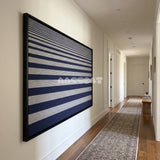 View of Linear Gradient framed textile wall art, featuring navy blue and light grey horizontal cotton cord stripes graduating from fine to broad bands.