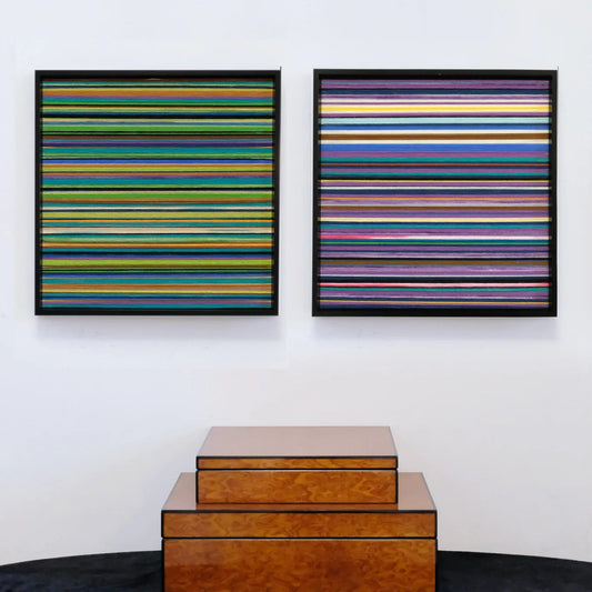 Reconstructing the Future hand-woven yarn art diptych with multicolor horizontal stripes on two square panels in natural wood frames, displayed above stacked wooden boxes.
